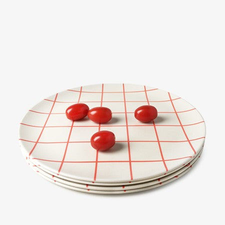 Four Xenia Taler 10" schoolhouse bamboo plates stack together with four tomatoes on top