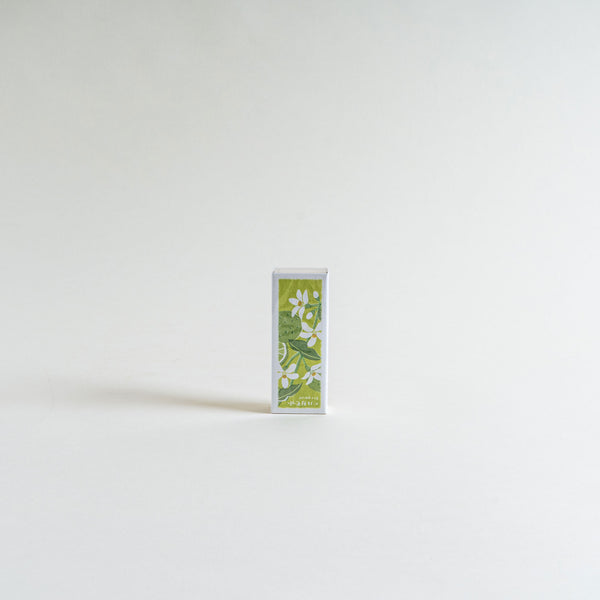 A slender box with a green design depicting bergamot fruits and leaves stands upright on a light background. The box contains bergamot-scented incense