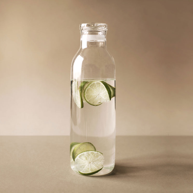 Kinto 1L Glass Bottlit Carafe with lime slices and water in it.