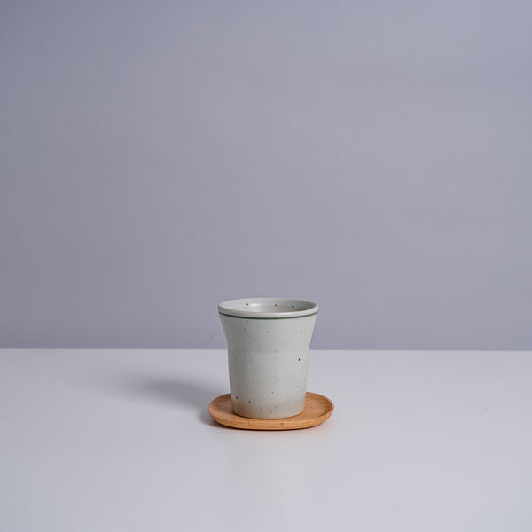 A ceramic teacup on a Kinto 4" UNITEA Coster in Beech