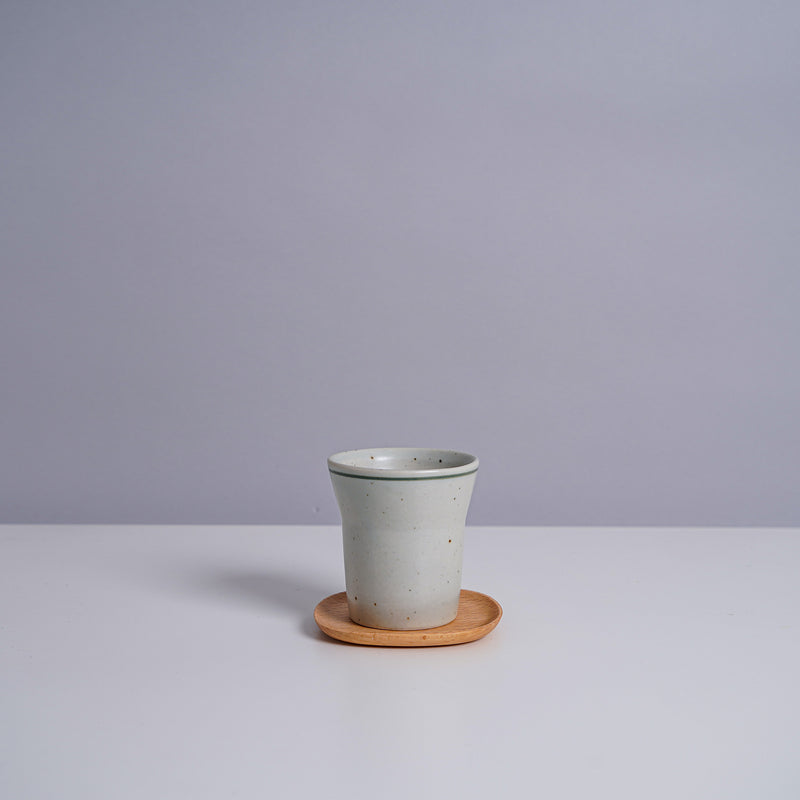 A ceramic teacup on a Kinto 4" UNITEA Coster in Beech