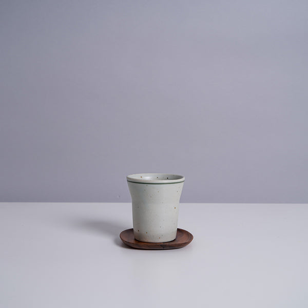 A ceramic teacup on a Kinto 4" UNITEA Coster in Walnut
