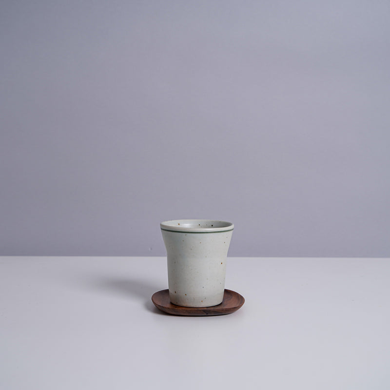 A ceramic teacup on a Kinto 4" UNITEA Coster in Walnut