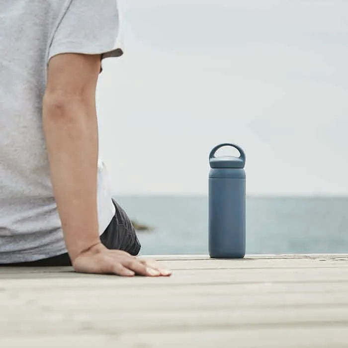 A person sitting outside with a Kinto Day Off Tumbler in Navy
