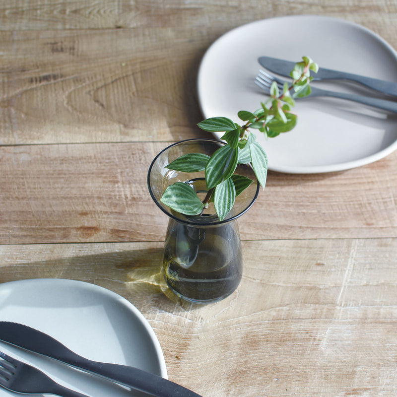 A Kinto small Aqua Culture Vase and two ceramic plates and dinner utensils on a wooden table
