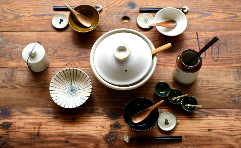 Studio M' white kamefuku donabe with some dinnerware on a wooden table